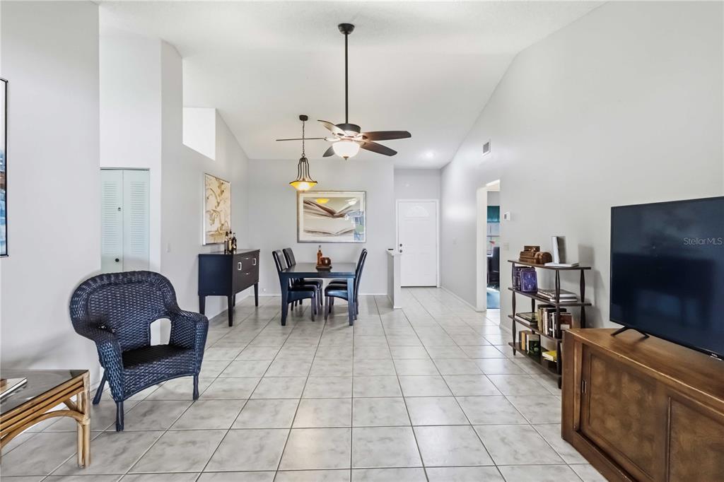 A dining area and living space feature light tile flooring, vaulted ceilings, and a ceiling fan — 13437 BEECHBERRY DRIVE, RIVERVIEW, FL