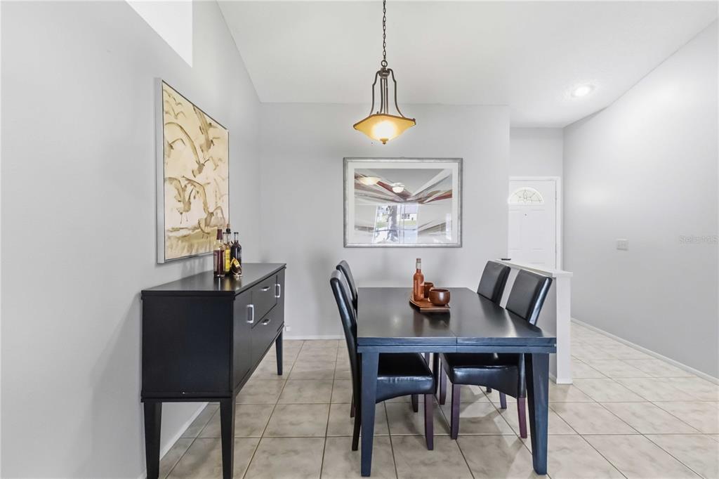 A dining room features a black table and sideboard, tile flooring, and a pendant light — 13437 BEECHBERRY DRIVE, RIVERVIEW, FL