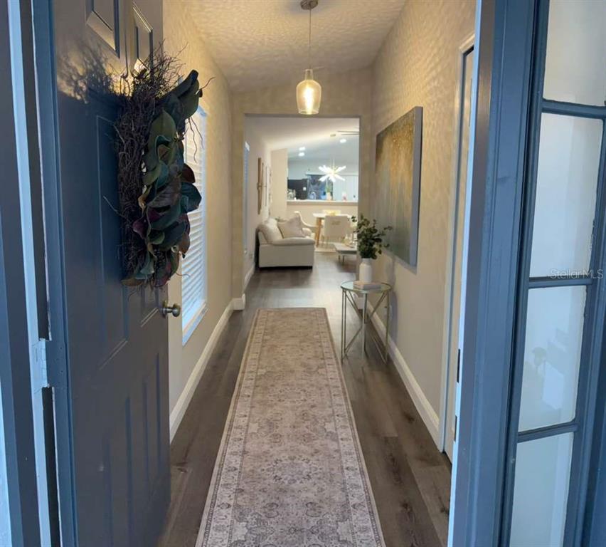 A view from a doorway looking down a hallway with wood flooring toward a living area — 11331 PALM ISLAND AVENUE, RIVERVIEW, FL