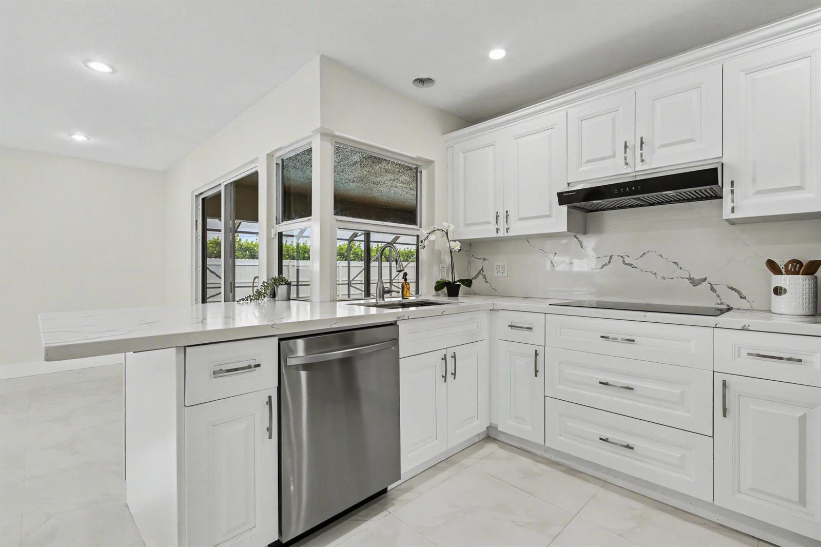 A modern kitchen features white cabinets, marble-look countertops, stainless steel appliances, and a corner window — 630 NW 79th Avenue, Margate FL 33063, MARGATE, FL