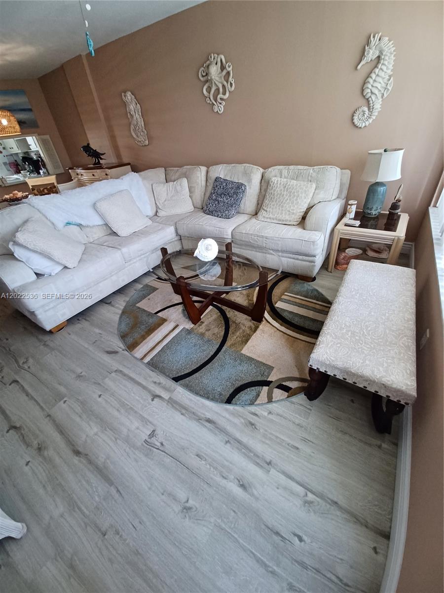 A living room features a large sectional sofa, a glass coffee table, and coastal wall decor — HALLANDALE BEACH, FL