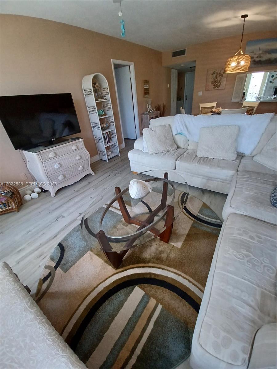 A living room features a sectional sofa, a glass coffee table, and a television stand — HALLANDALE BEACH, FL
