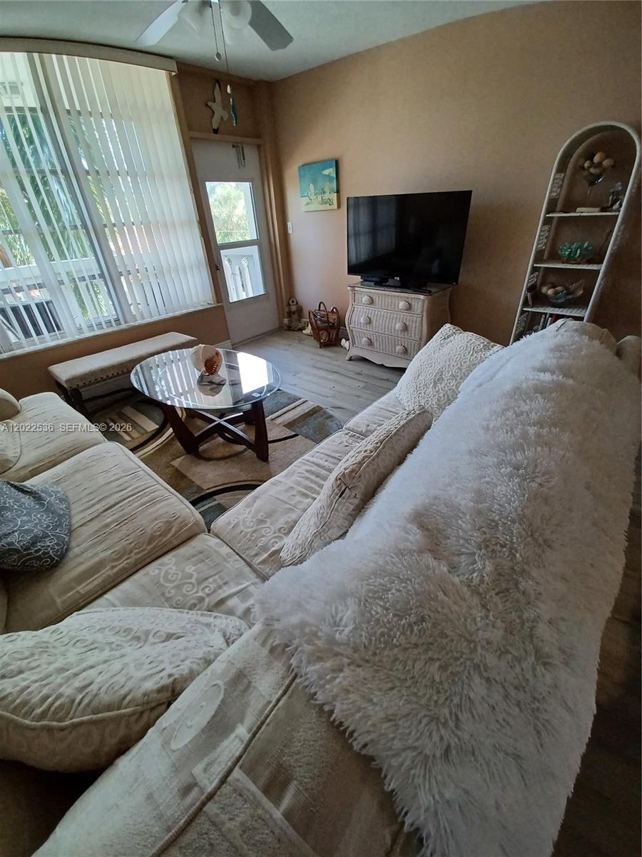 A living room features a sectional sofa, a glass coffee table, and a television stand — HALLANDALE BEACH, FL