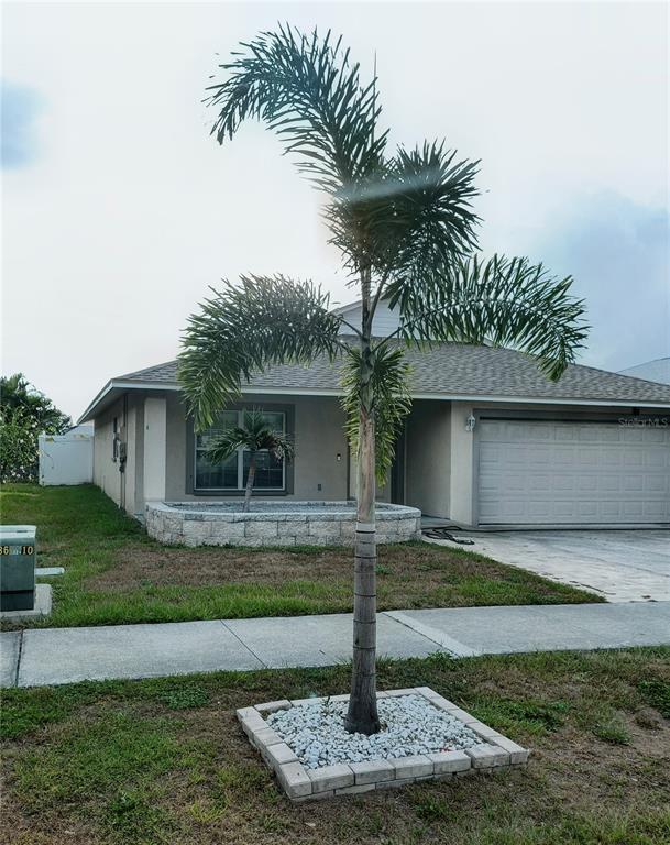 A single-story house with a beige exterior, a two-car garage, and two palm trees — 1213 HUMBLE HAVEN STREET, RUSKIN, FL