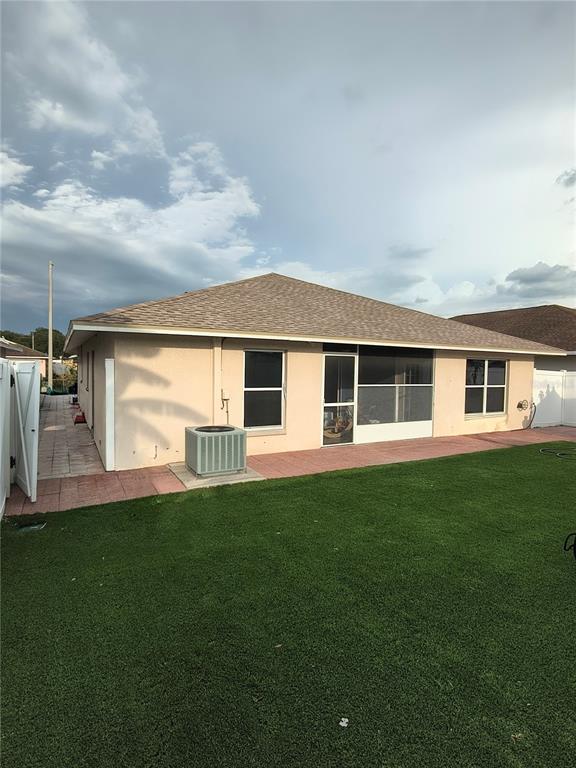 The exterior of a house features a tan stucco wall, a screened-in porch, and a yard — 1213 HUMBLE HAVEN STREET, RUSKIN, FL