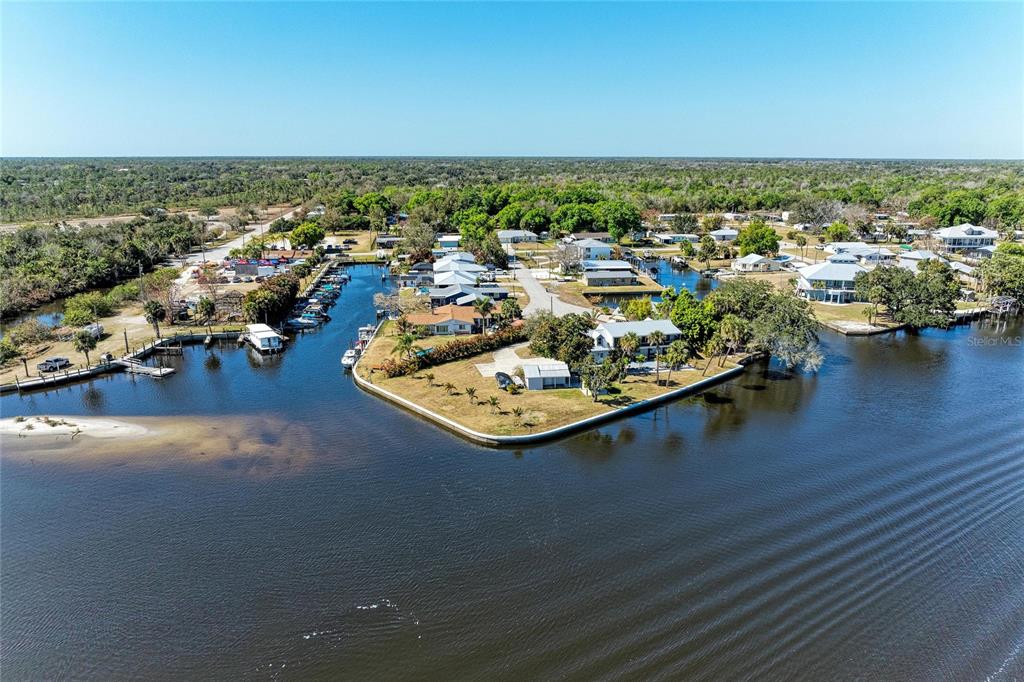 An aerial view shows waterfront houses along a canal with boat docks and surrounding trees — 9610 SW YACHT DRIVE, ARCADIA, FL