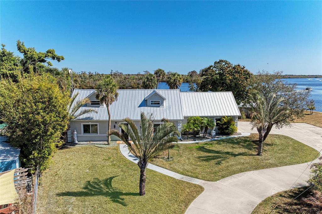 An aerial view of a single-story house with a metal roof near the water — 9610 SW YACHT DRIVE, ARCADIA, FL