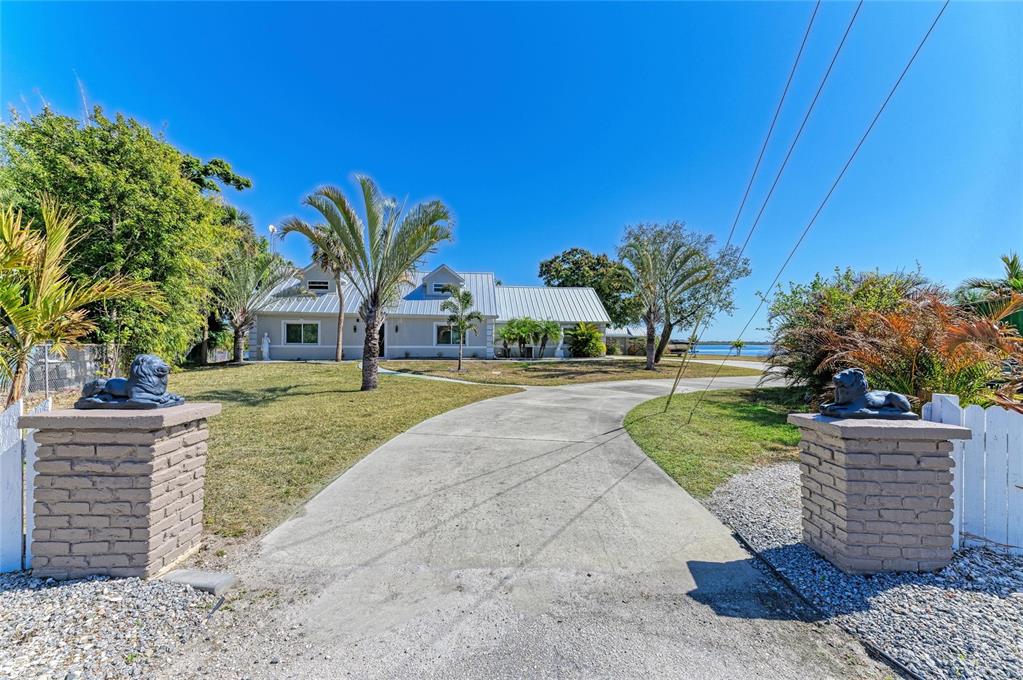 A concrete driveway leads to a house with a metal roof and two lion statues — 9610 SW YACHT DRIVE, ARCADIA, FL