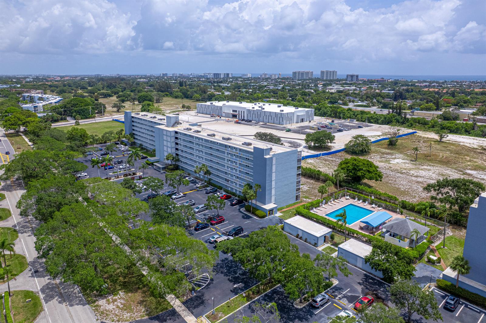An aerial view shows a multi-story apartment building with a parking lot and swimming pool — 5700 NW 2nd Avenue # 705, Boca Raton FL 33487, BOCA RATON, FL