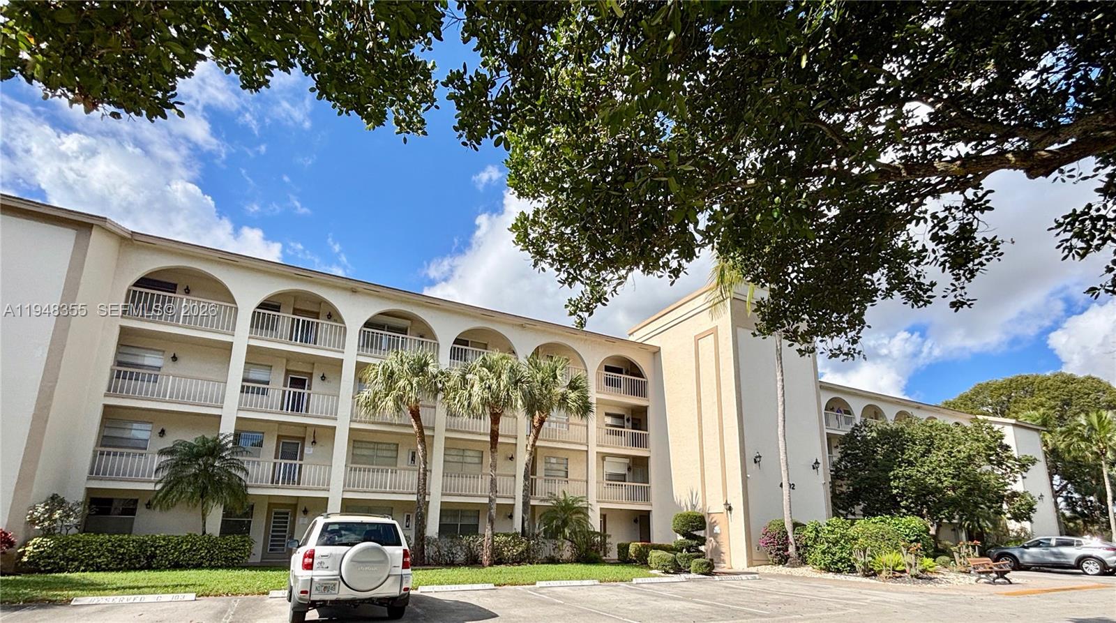 A multi-story apartment building with arched balconies and a parking lot in front — 4602 Martinique Way # E3, Coconut Creek FL 33066, COCONUT CREEK, FL