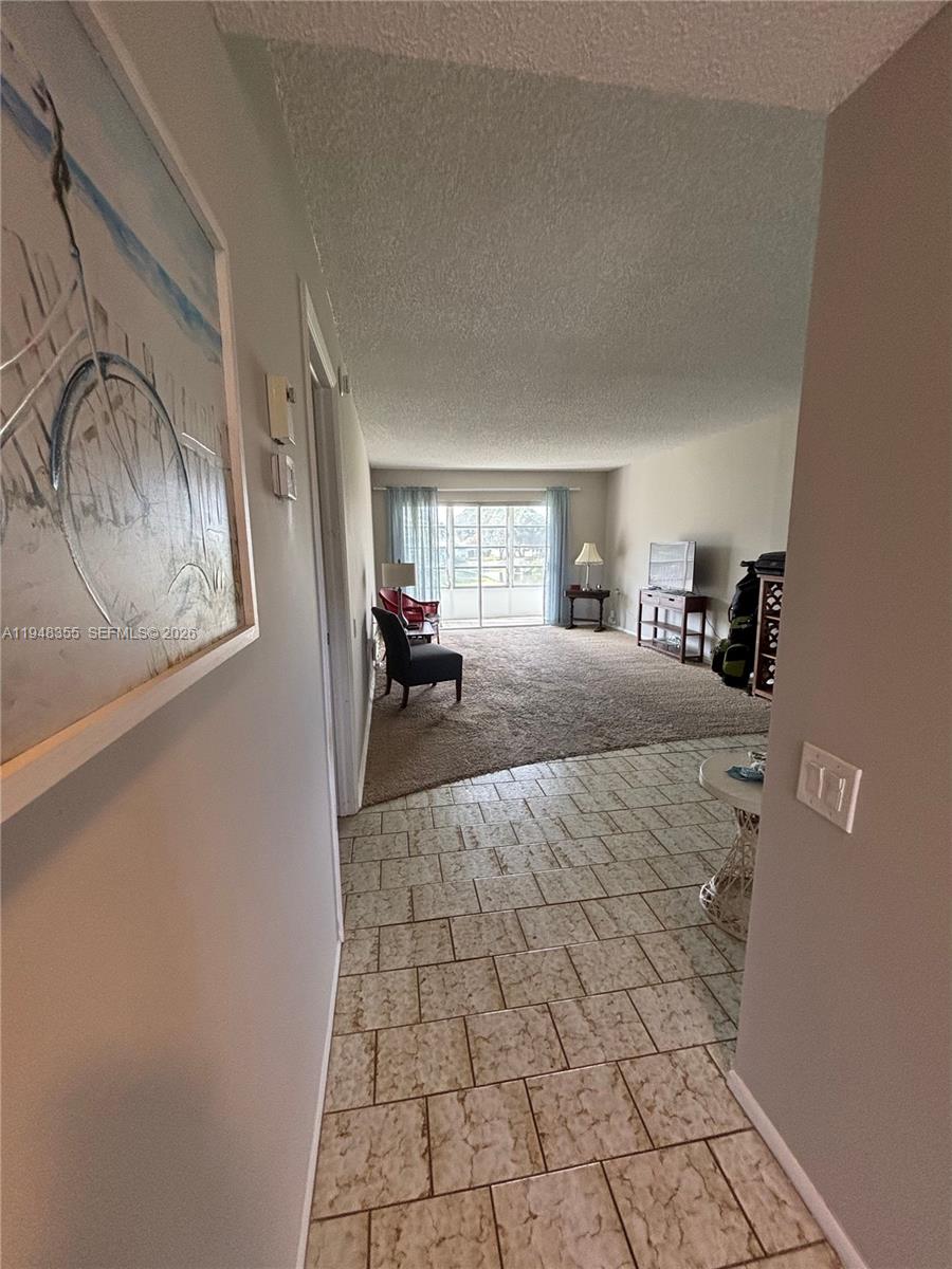 A tiled entryway leads into a carpeted living room with a sliding glass door — 4602 Martinique Way # E3, Coconut Creek FL 33066, COCONUT CREEK, FL