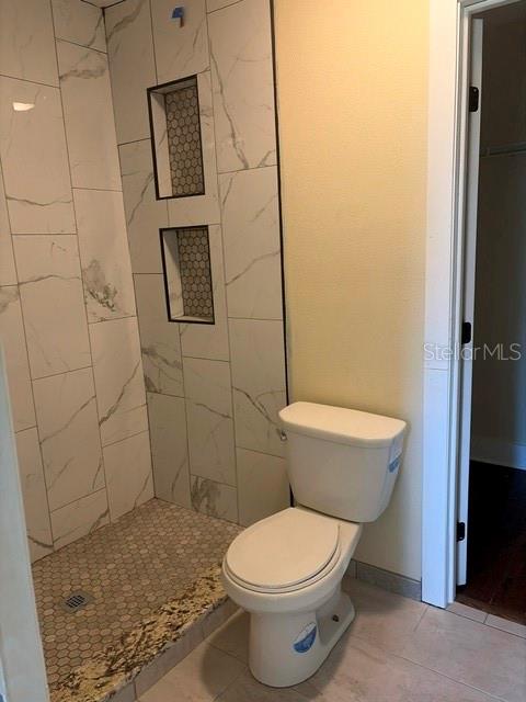 A bathroom features a walk-in shower with white marble-look tiles and a white toilet — 840 N FRANKFORT AVENUE, DELAND, FL