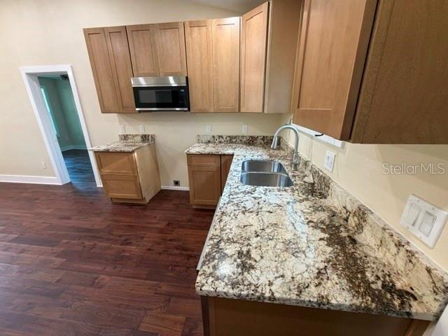 A kitchen features light wood cabinets, granite countertops, a stainless steel microwave, and dark flooring — 840 N FRANKFORT AVENUE, DELAND, FL