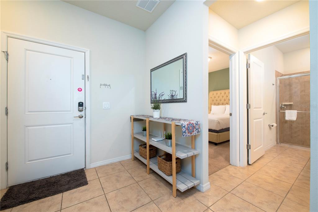 An entryway with tile flooring, a console table, a mirror, and doors leading to rooms — 4611 TERRASONESTA DRIVE, DAVENPORT, FL
