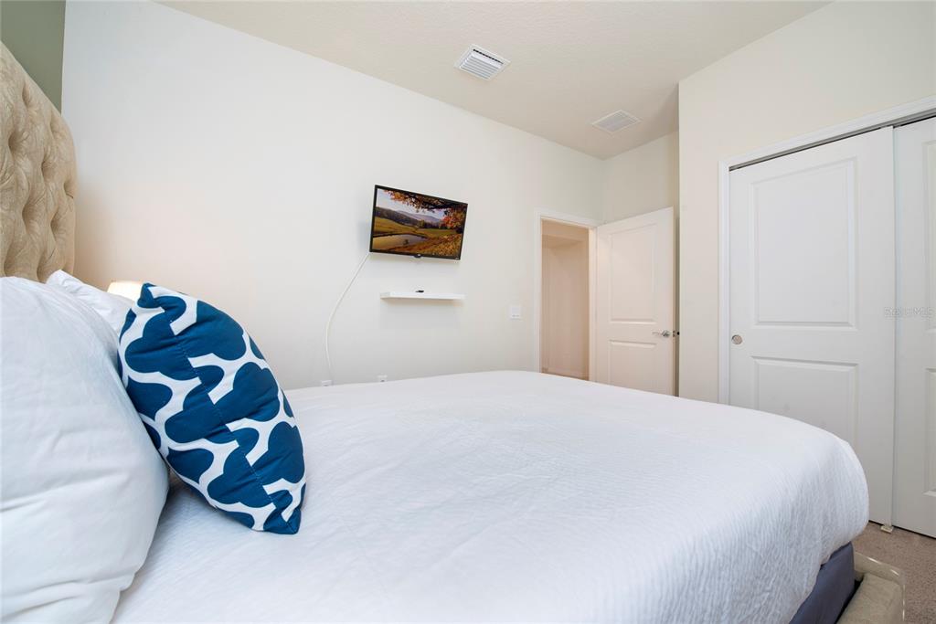 A bedroom features a bed with patterned pillows, a wall-mounted television, and a closet — 4611 TERRASONESTA DRIVE, DAVENPORT, FL