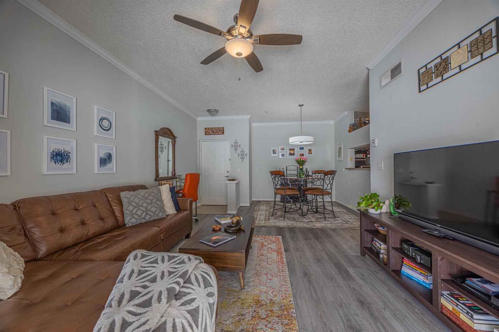 A living room with a brown leather sofa, coffee table, television, and dining area — 2412 Tuscany Way, Boynton Beach FL 33435, BOYNTON BEACH, FL