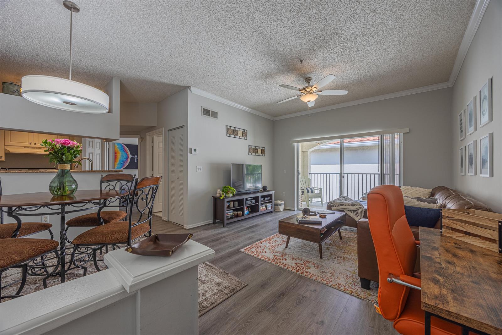 A living and dining area with wood-look flooring, a ceiling fan, and a sliding glass door — 2412 Tuscany Way, Boynton Beach FL 33435, BOYNTON BEACH, FL