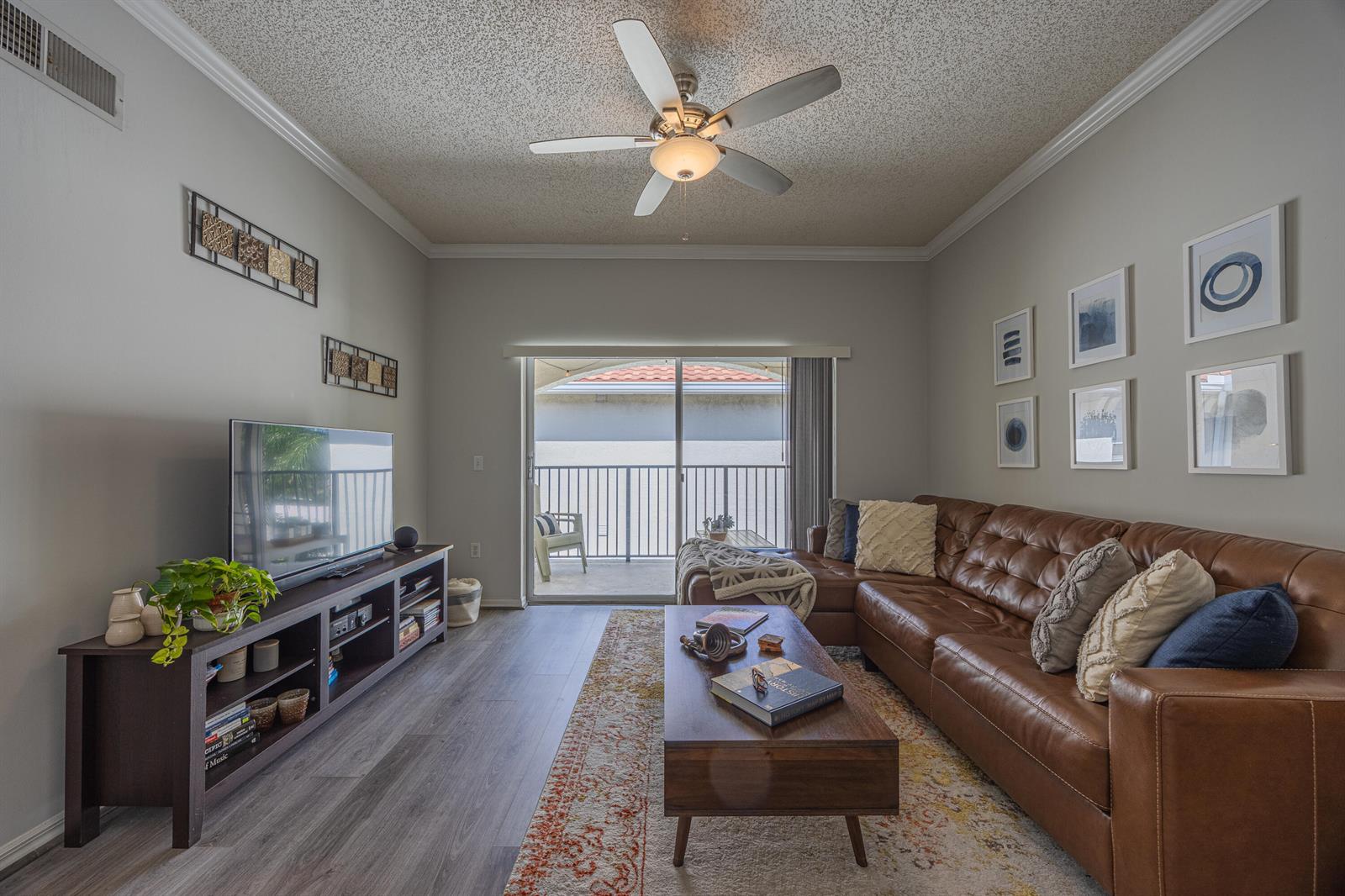 A living room features a brown leather sectional, a wood coffee table, and a television console — 2412 Tuscany Way, Boynton Beach FL 33435, BOYNTON BEACH, FL