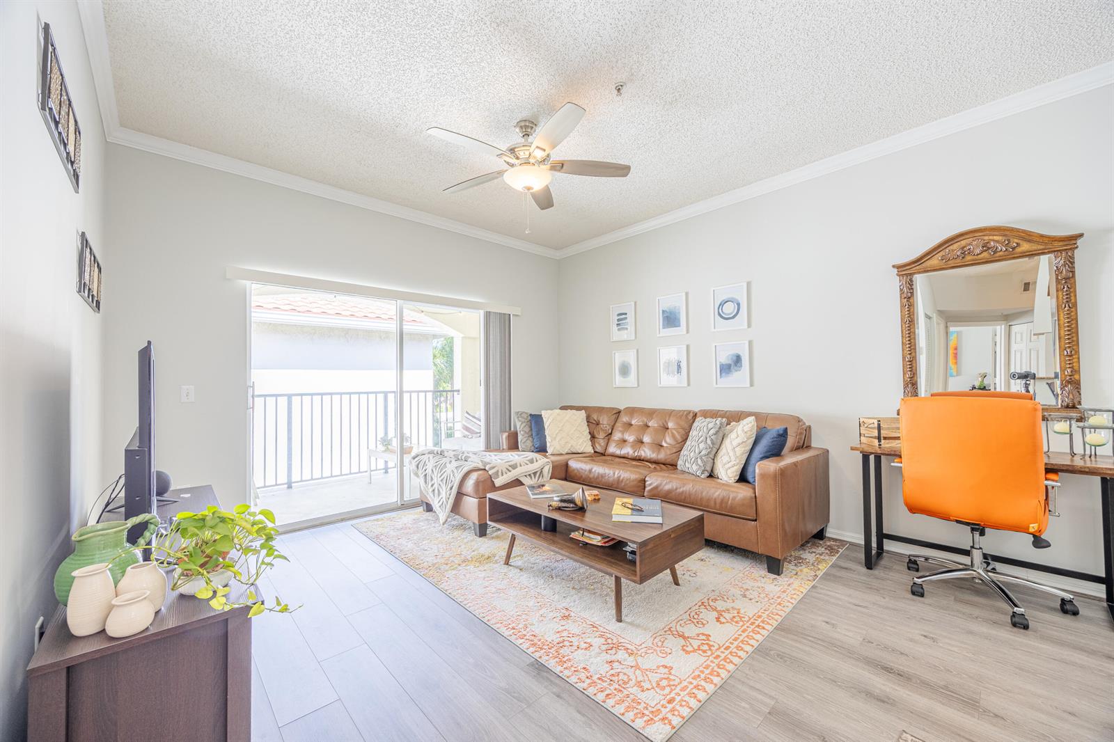 A living room features a brown leather sectional, a coffee table, and an orange office chair — 2412 Tuscany Way, Boynton Beach FL 33435, BOYNTON BEACH, FL