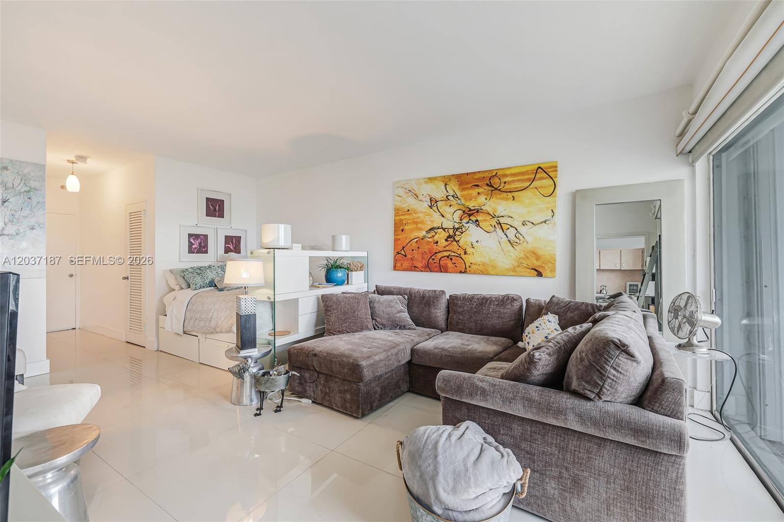 A studio apartment features a sectional sofa, a bed, and a large abstract painting — 3 Island Ave # 14A, Miami Beach FL 33139, MIAMI BEACH, FL