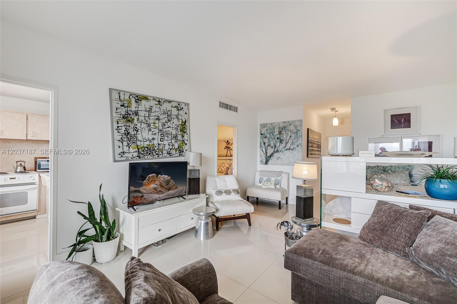A bright living room features white tile floors, a television, and a brown sectional sofa — 3 Island Ave # 14A, Miami Beach FL 33139, MIAMI BEACH, FL