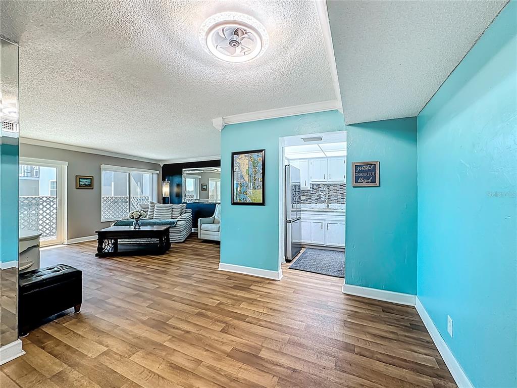 A living room with wood-look flooring leads into a kitchen with light blue walls — 2901 26TH STREET W UNIT 511, BRADENTON, FL