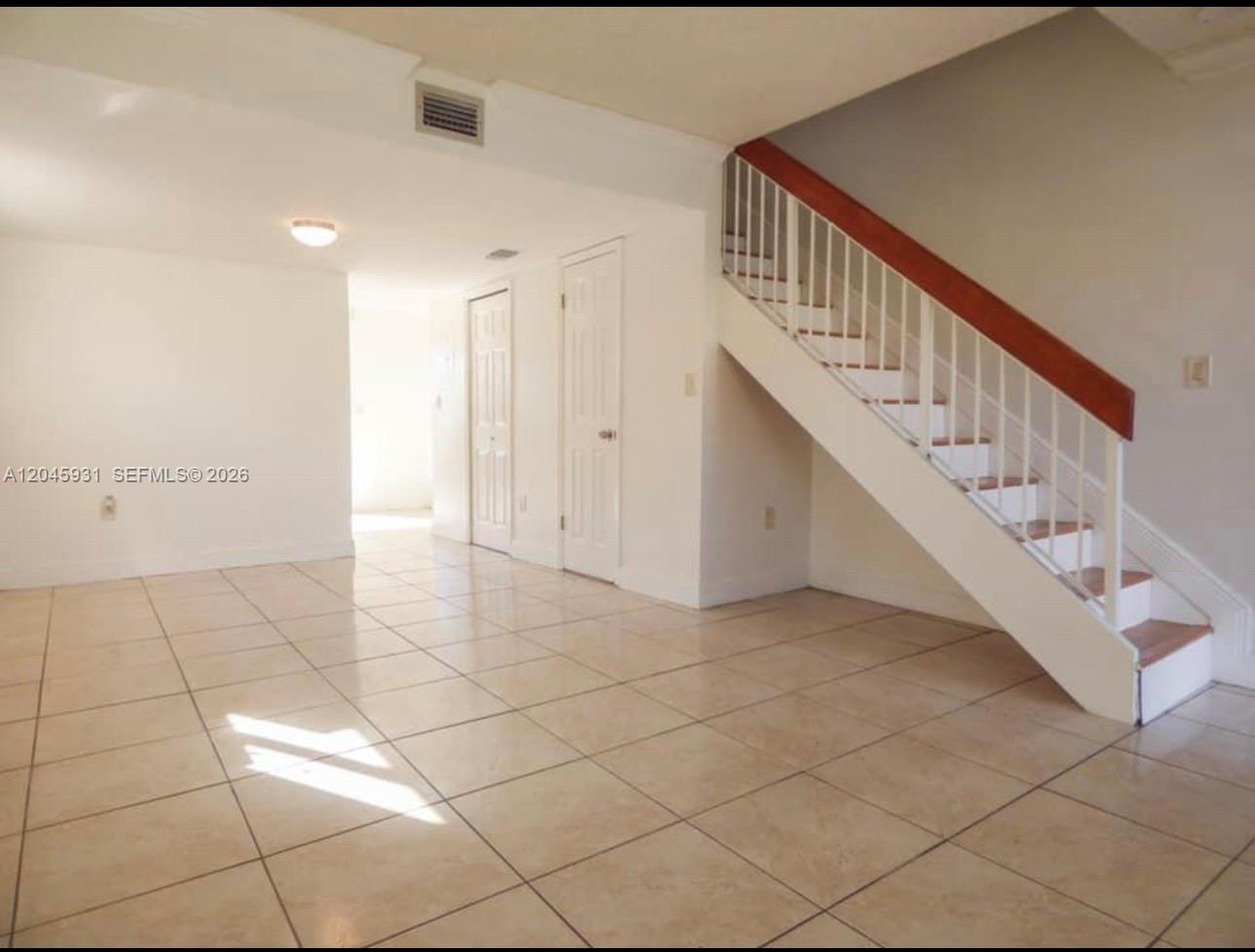 An interior view shows a tiled living area with a staircase and two closed doors — 8252 NW 6th Ter # 235, Miami FL 33126, MIAMI, FL