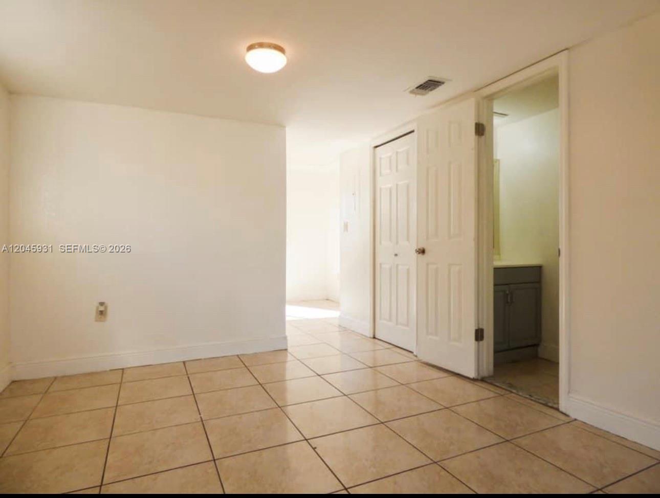 A room with beige tile flooring, white walls, a ceiling light, and an open bathroom — 8252 NW 6th Ter # 235, Miami FL 33126, MIAMI, FL