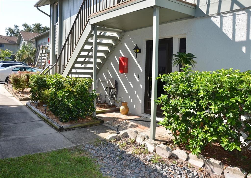 An exterior view of a ground-floor apartment entrance with a staircase and landscaping — 1960 UNION STREET UNIT 19, CLEARWATER, FL
