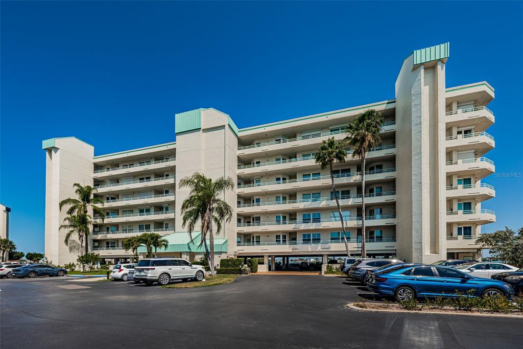 A multi-story apartment building with balconies and a parking lot in the foreground — 7979 SAILBOAT KEY BOULEVARD S UNIT 205, SOUTH PASADENA, FL