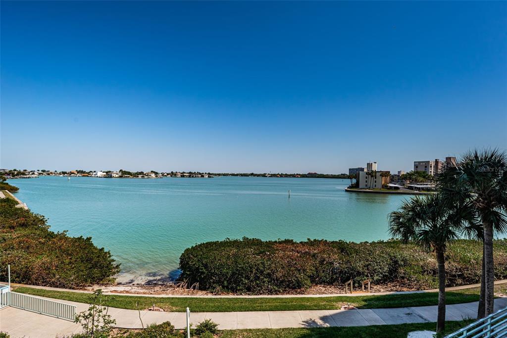 A view of a calm bay with a shoreline, palm trees, and distant buildings — 7979 SAILBOAT KEY BOULEVARD S UNIT 205, SOUTH PASADENA, FL