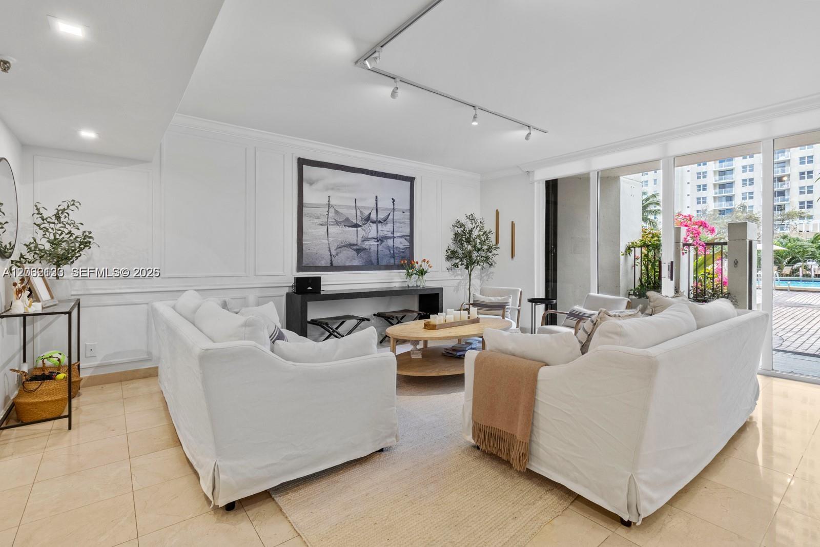 A bright living room features white slipcovered sofas, a wooden coffee table, and sliding glass doors — 520 Brickell Key Dr # A307, Miami FL 33131, MIAMI, FL