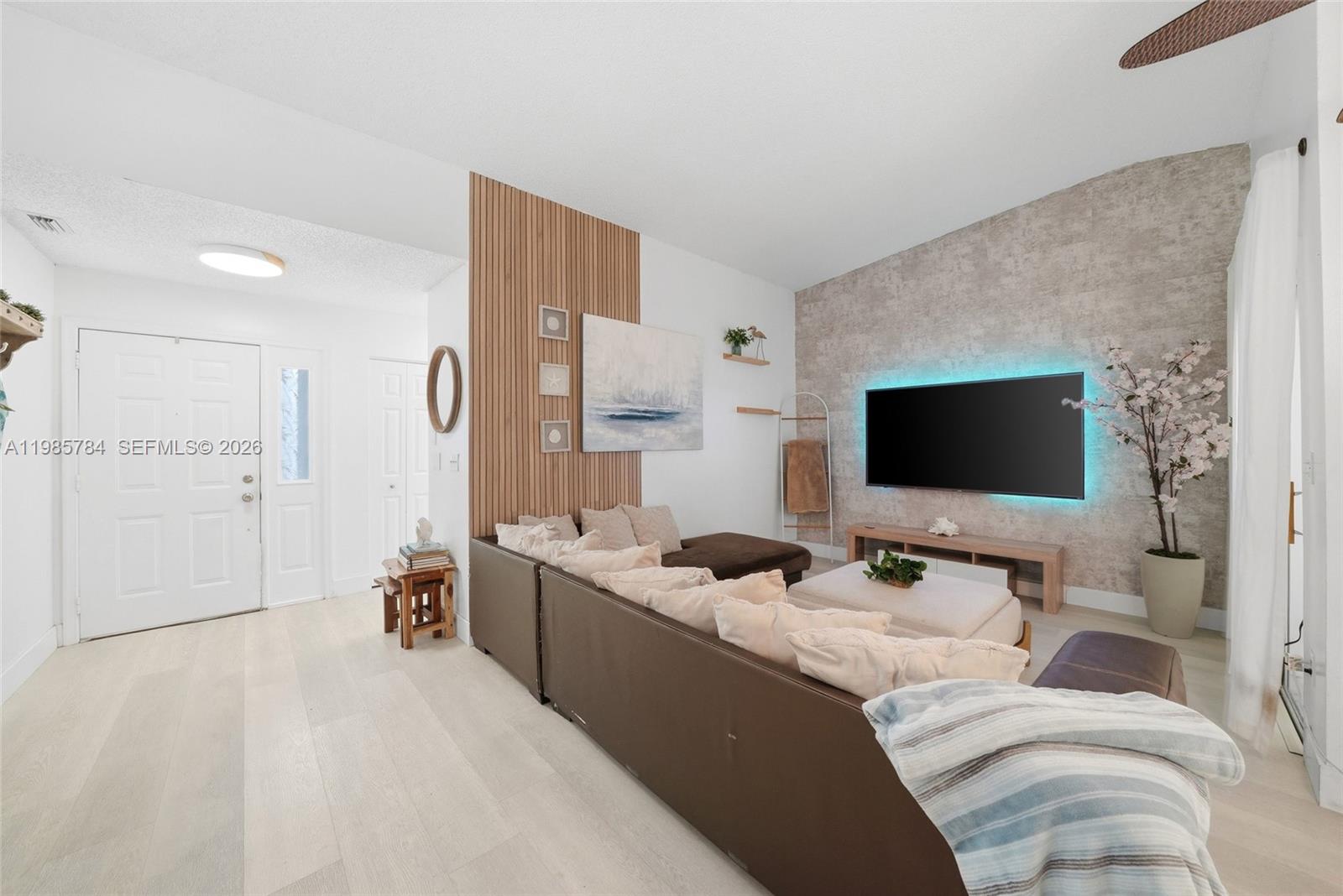 A living room features a wood-slat accent wall, a textured feature wall, and a sectional sofa — 677 SE 22nd Dr, Homestead FL 33033, HOMESTEAD, FL