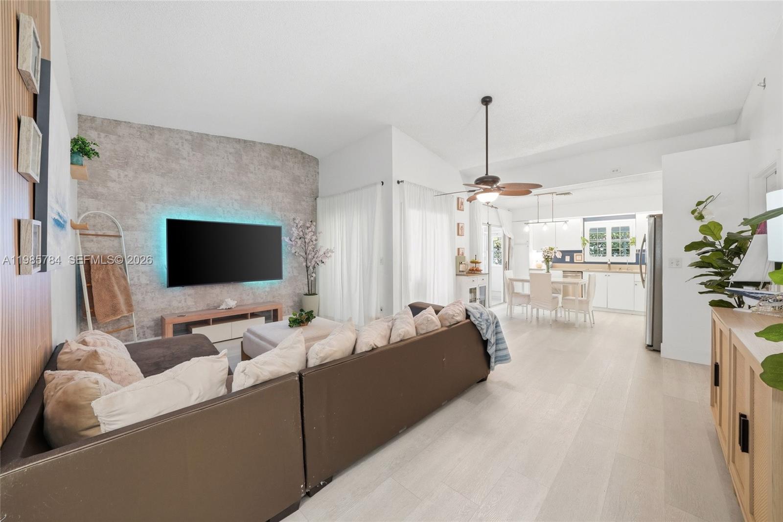 A living room with a textured accent wall, sectional sofa, and an open-concept kitchen — 677 SE 22nd Dr, Homestead FL 33033, HOMESTEAD, FL