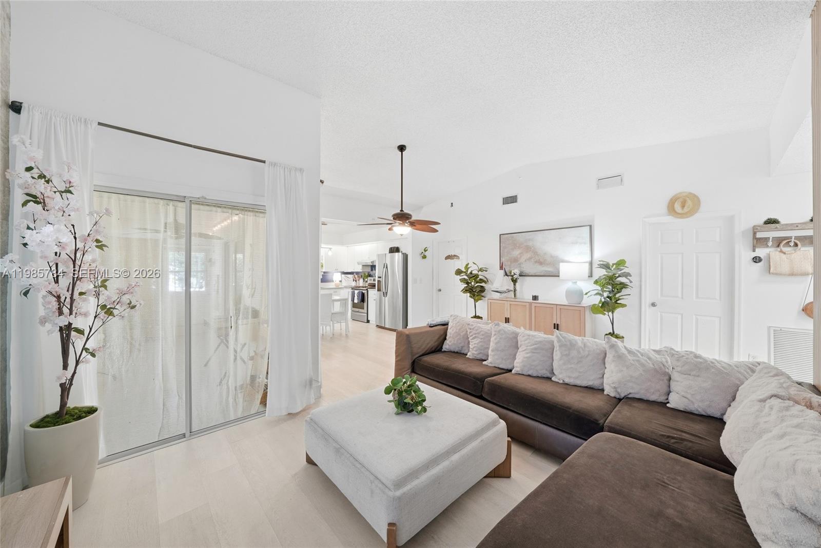 A living room features a large brown sectional sofa, a light-colored ottoman, and sliding glass doors — 677 SE 22nd Dr, Homestead FL 33033, HOMESTEAD, FL