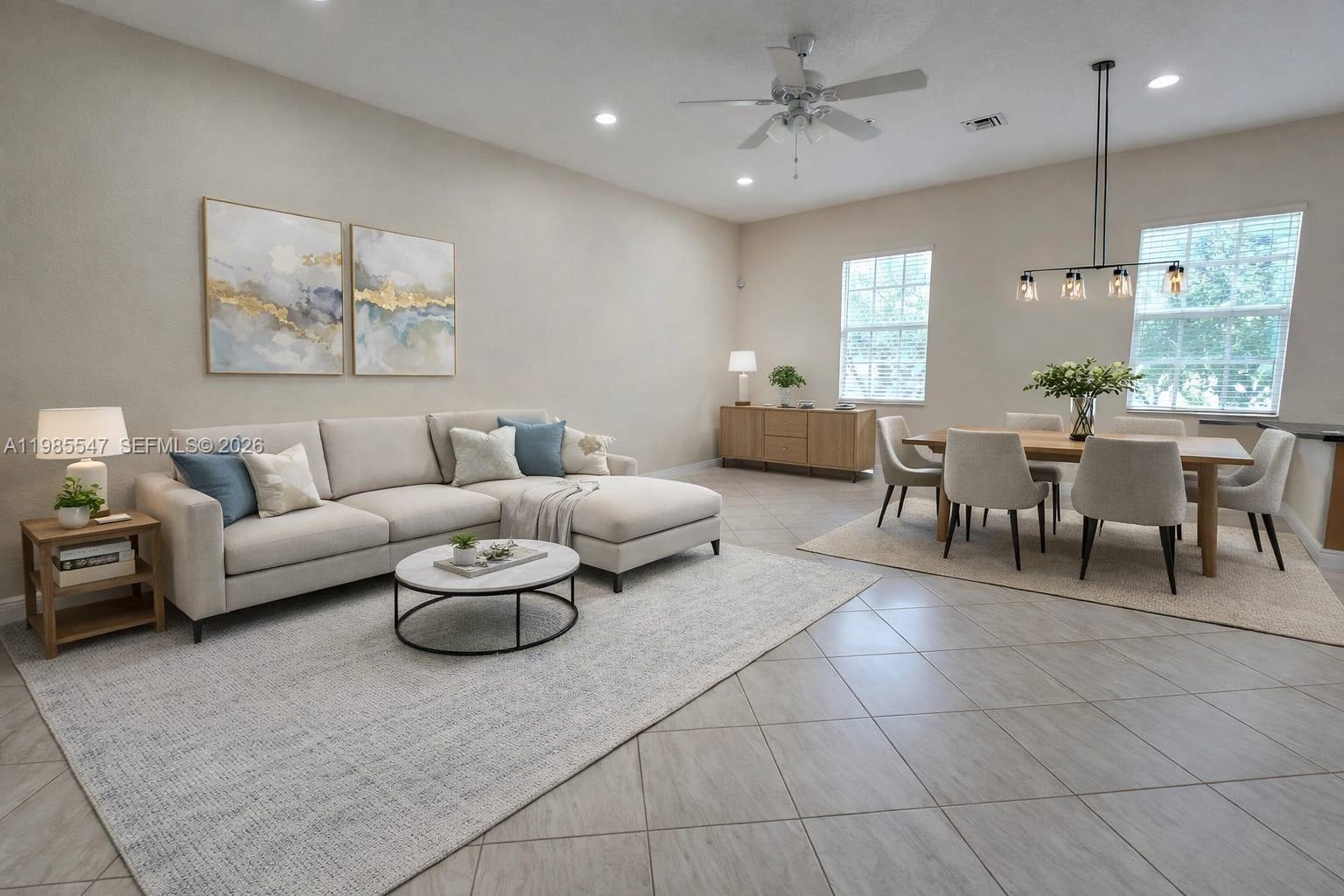A bright open-concept living and dining area features neutral furniture, tile flooring, and modern lighting — 6841 N Lakeside Cir N # 1, Davie FL 33314, DAVIE, FL