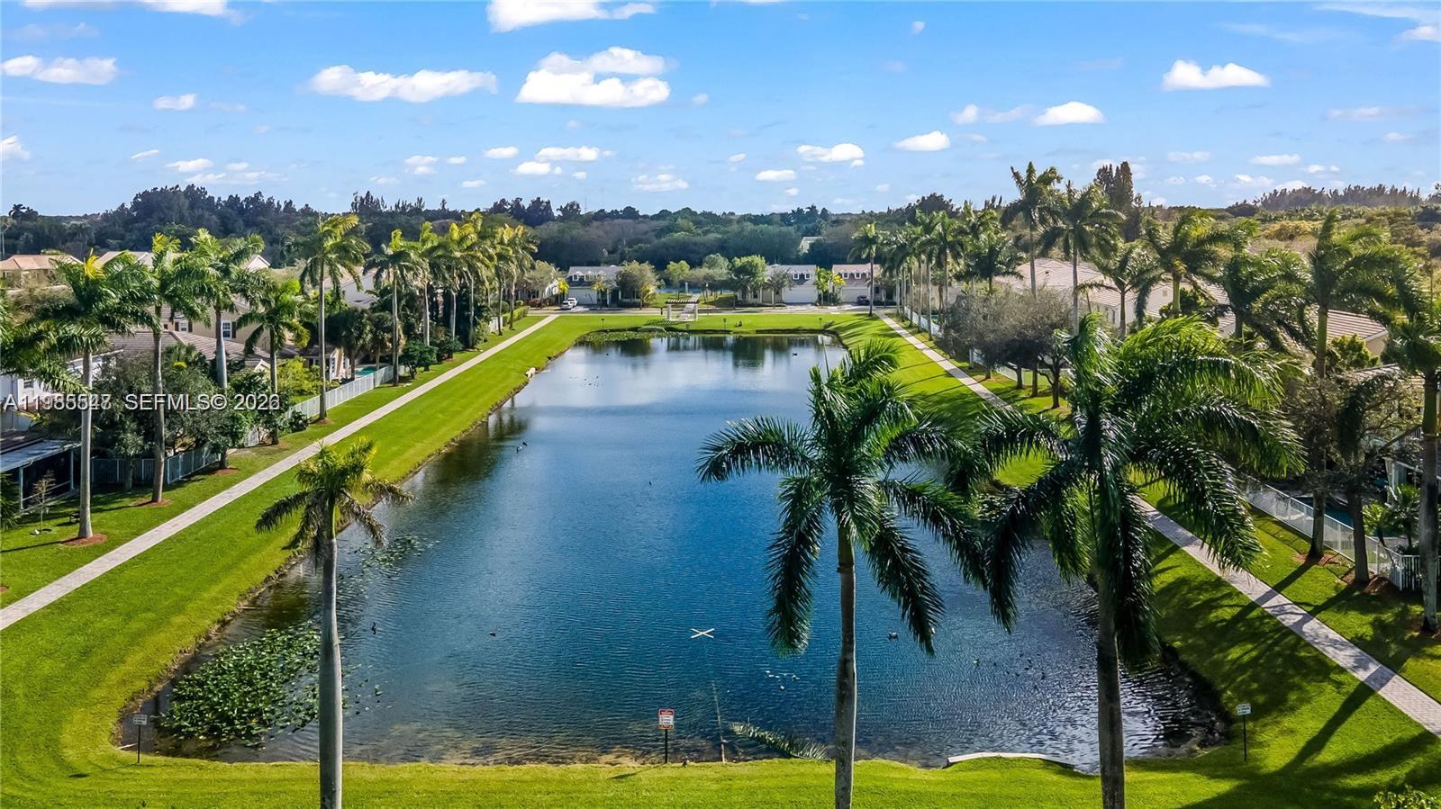 An aerial view shows a rectangular pond surrounded by palm trees and residential houses — 6841 N Lakeside Cir N # 1, Davie FL 33314, DAVIE, FL