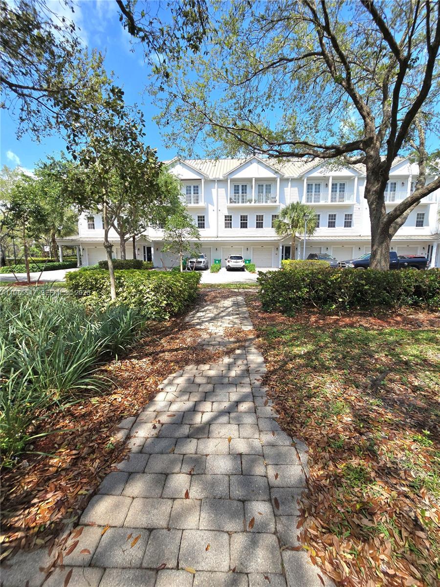 A stone path leads toward a multi-story white townhouse complex with attached garages — 6841 N Lakeside Cir N # 1, Davie FL 33314, DAVIE, FL
