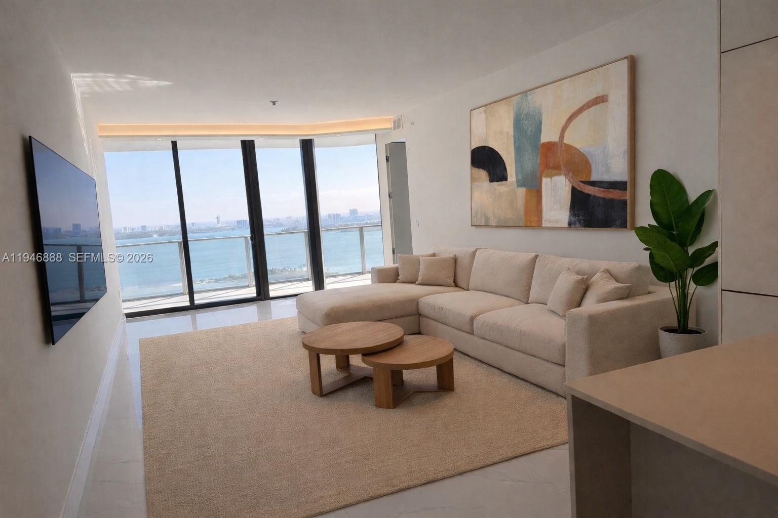 A modern living room features a beige sectional sofa, nested coffee tables, and floor-to-ceiling windows — 700 NE 24TH # 3105, Miami FL 33137, MIAMI, FL