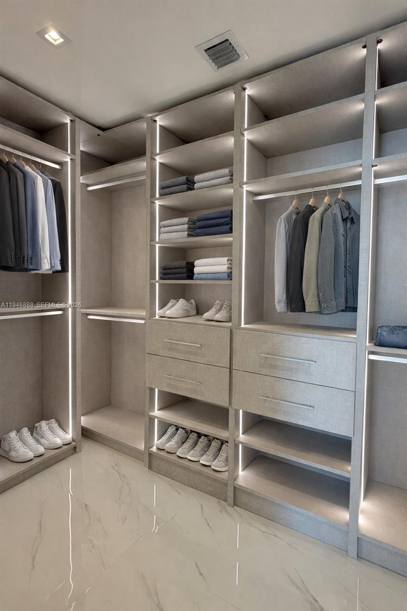 A walk-in closet features light wood shelving, integrated LED lighting, and white marble flooring — 700 NE 24TH # 3105, Miami FL 33137, MIAMI, FL