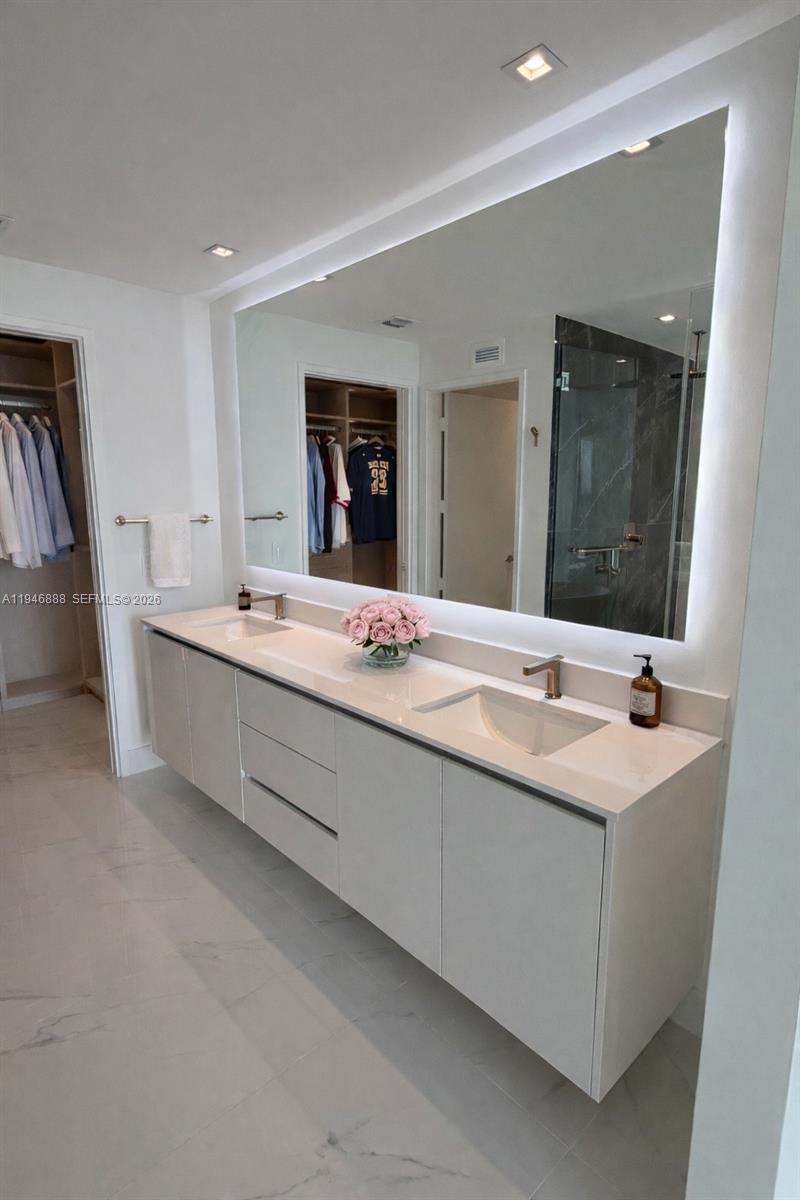 A modern bathroom features a double vanity with white cabinets, quartz countertops, and a large mirror — 700 NE 24TH # 3105, Miami FL 33137, MIAMI, FL