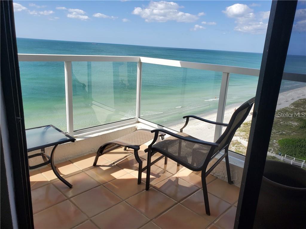 A balcony with tile flooring, patio furniture, and a glass railing overlooking the ocean — 1050 LONGBOAT CLUB ROAD UNIT 1006, LONGBOAT KEY, FL