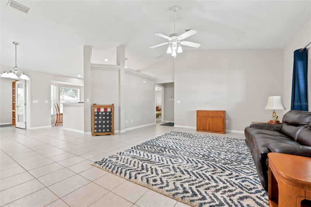 A living room with tile floors, a patterned area rug, a leather sofa, and ceiling fan — 8708 SW 60TH CIRCLE, OCALA, FL