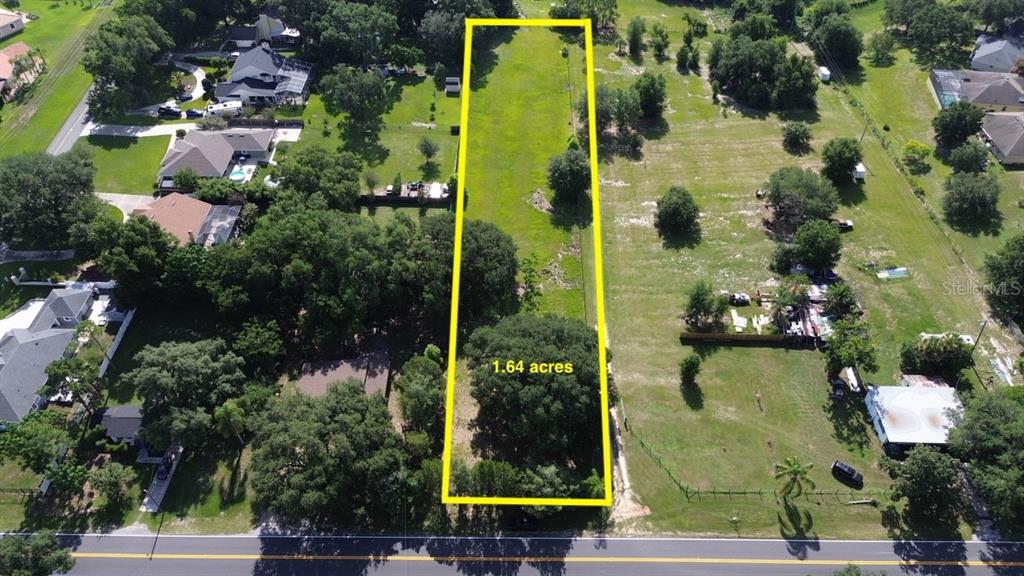 An aerial view shows a rectangular, tree-covered vacant lot outlined in yellow — 11750 COUNTY ROAD 561, CLERMONT, FL