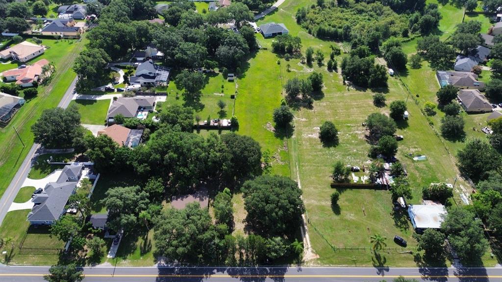 An aerial view shows a large, grassy residential lot situated between several houses and trees — 11750 COUNTY ROAD 561, CLERMONT, FL