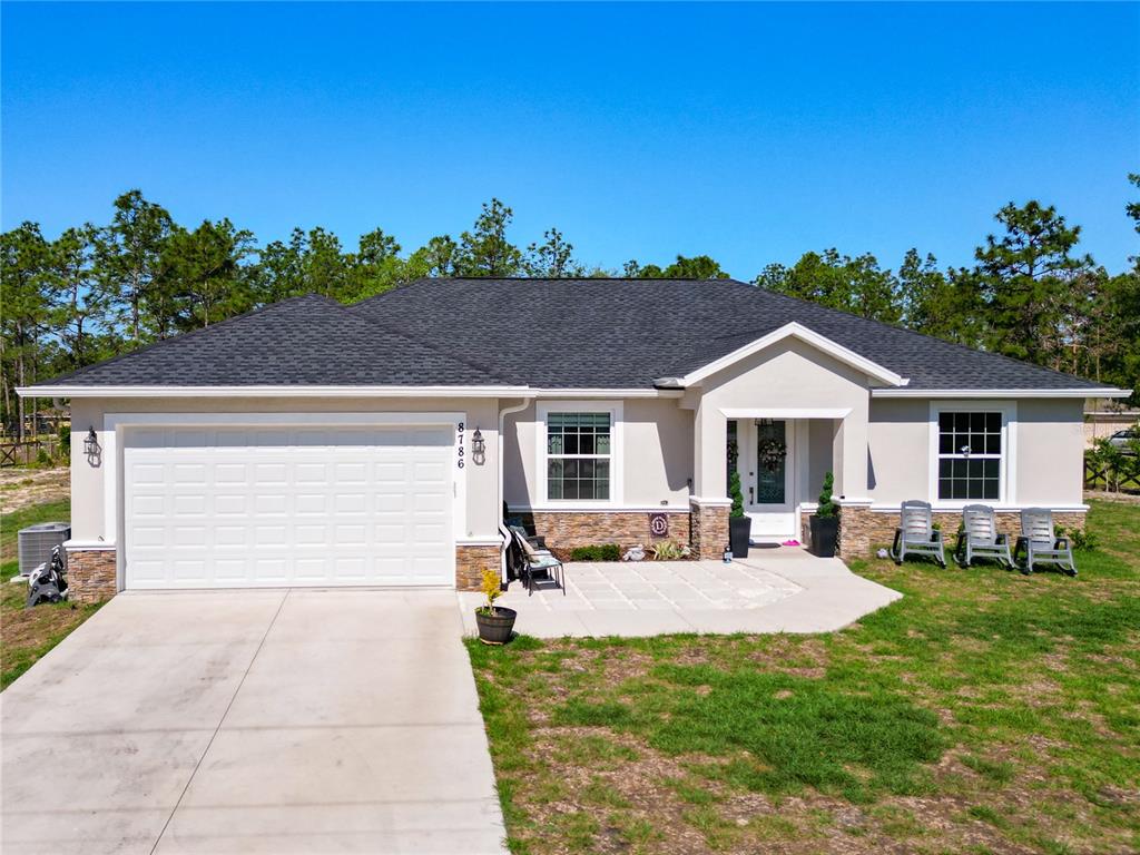 A single-story house with a white garage, stone accents, and a paved front patio — 8786 SW 127TH AVENUE, DUNNELLON, FL