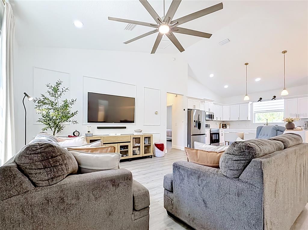 A living room with gray sofas, a ceiling fan, and an open-concept kitchen — 8786 SW 127TH AVENUE, DUNNELLON, FL