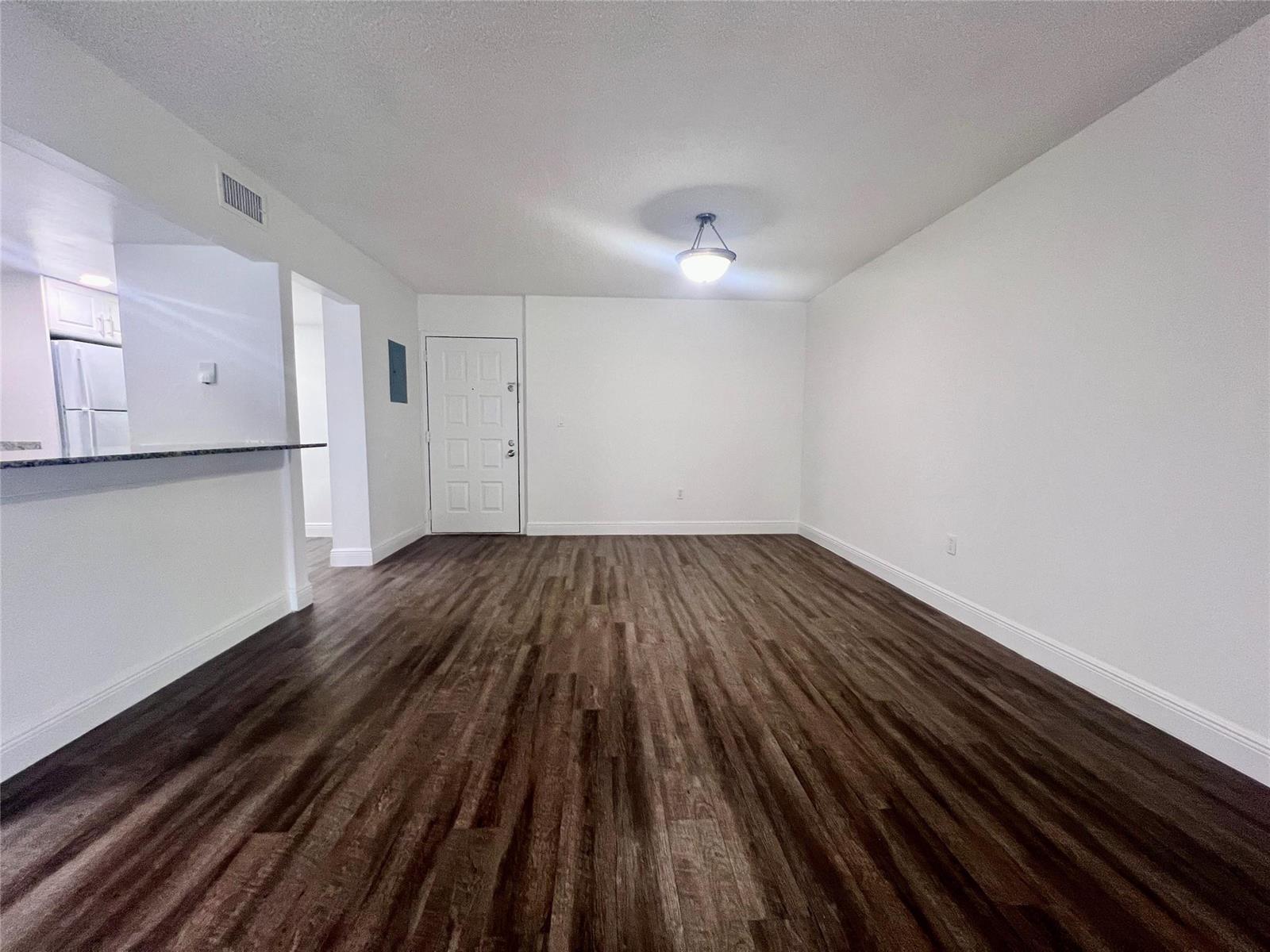 An empty living room features white walls, dark wood-look flooring, and a single ceiling light — 17350 NW 68th Avenue # 419, Hialeah FL 33015, HIALEAH, FL
