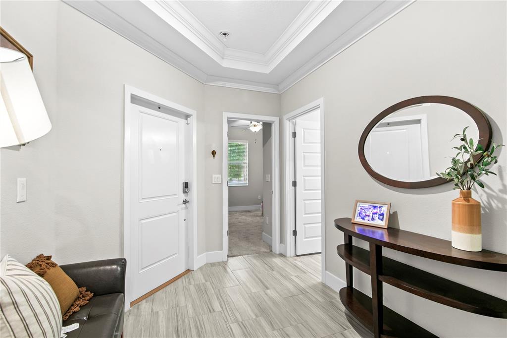 An entryway features light tile flooring, a dark wood console table, and a white door — 9890 RED BAY LOOP, LAND O LAKES, FL