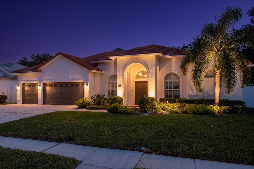 A single-story house with a tile roof, garage, and arched entryway at dusk — 2801 SHORE BREEZE DRIVE, TAMPA, FL
